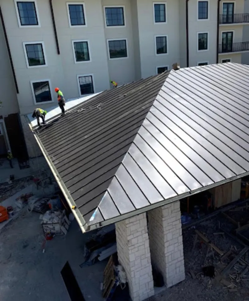 Crew installing standing seam metal roof panels on a commercial project in Cicero